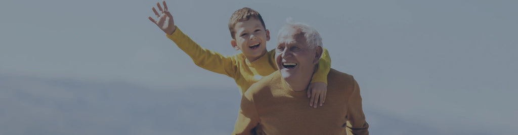 A man with white hair giving a piggyback ride to a young boy.