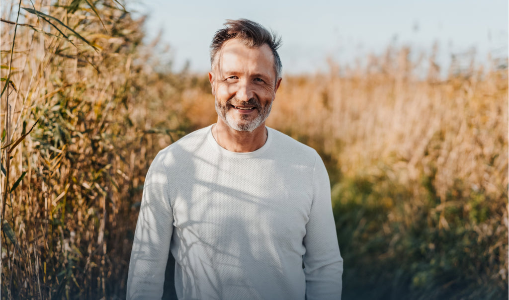 A man in a white shirt standing in a field of long grass.