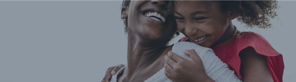 A mother carrying and smiling with her daughter.