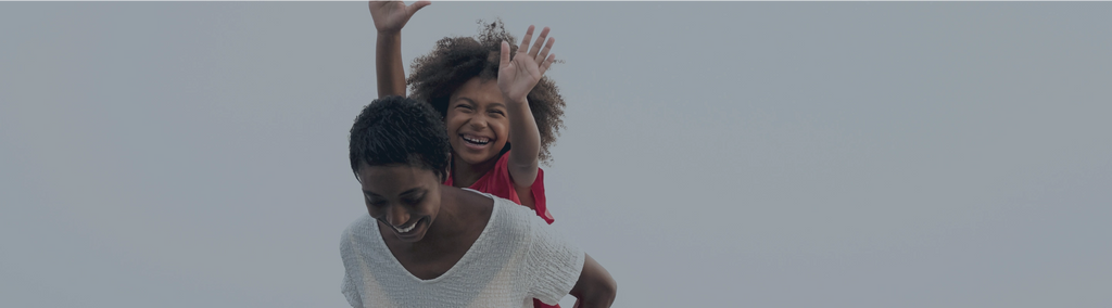 A woman giving a smiling child a piggyback ride.