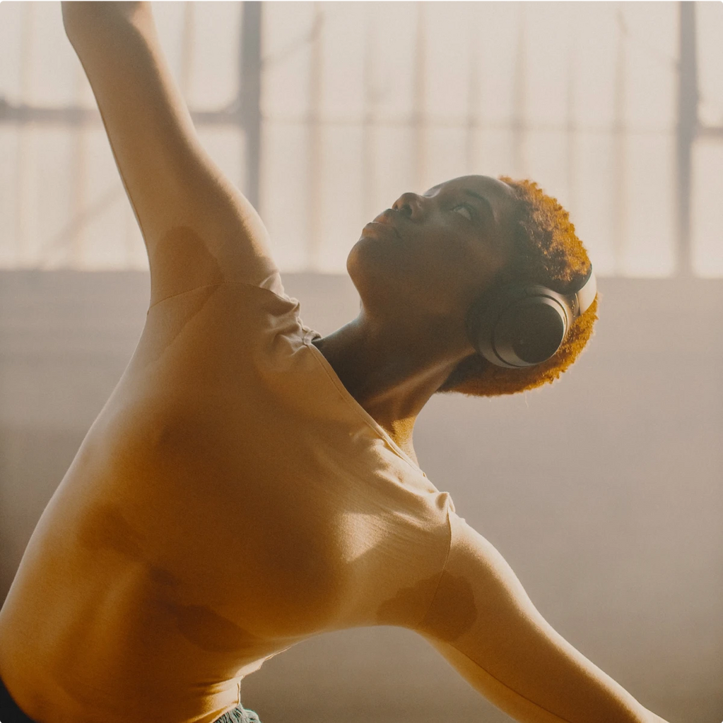 A woman wearing headphones and doing yoga.