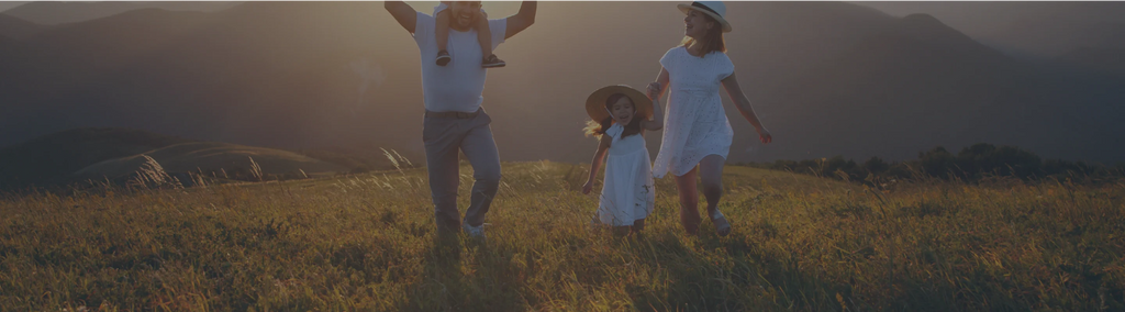 A family of four outside in a field with mountains in the background.