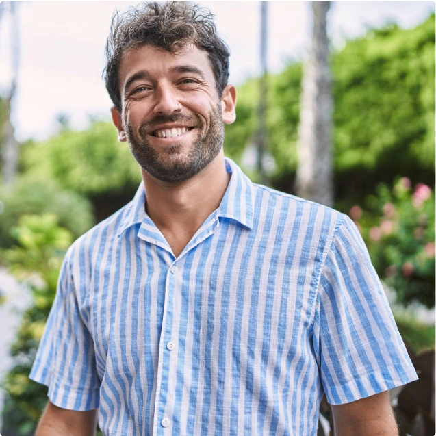 A man standing outside wearing a blue striped shirt.