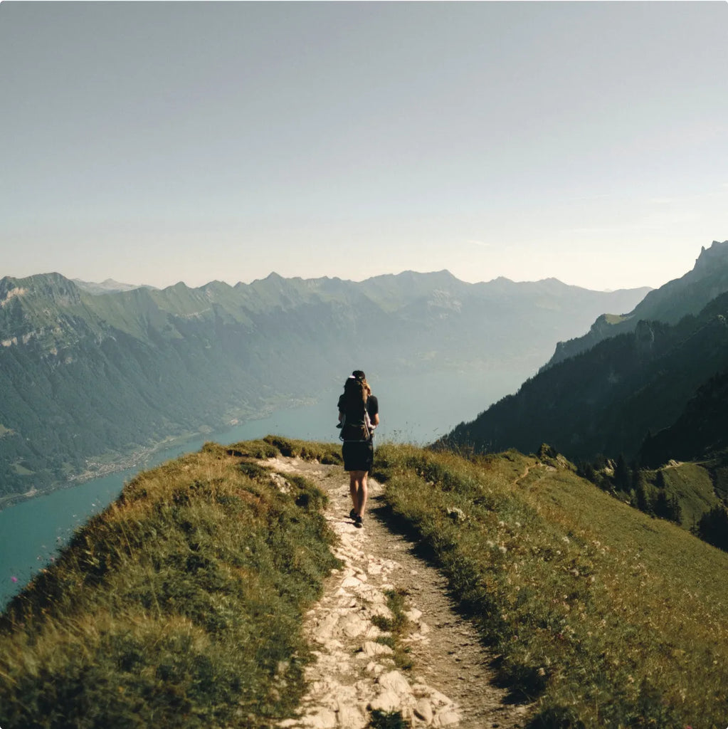 A person hiking along a mountain trail with a landscape view.