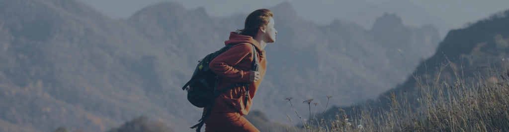 A person hiking up a mountain with more mountains in the background.